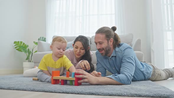 Caucasian happy loving parent play with baby toddler in living room.