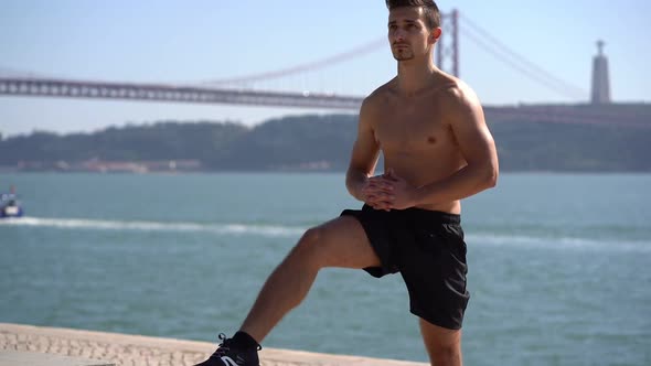 Focused Bare-chested Sportsman Exercising Near River