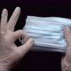 Doctor showing surgical face mask holds in hands protected white medical gloves on black background - VideoHive Item for Sale