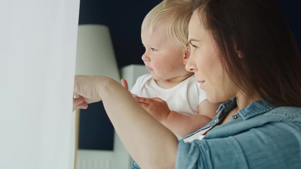 Tilt up video of mother and baby standing next to the window. Shot with RED helium camera in 8K 