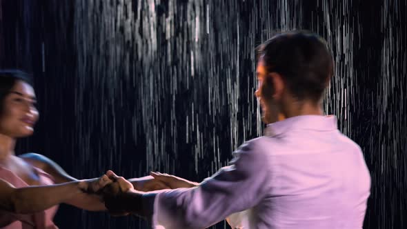 Happy Loving Couple Whirls Holding Hands on the Background of the Rain