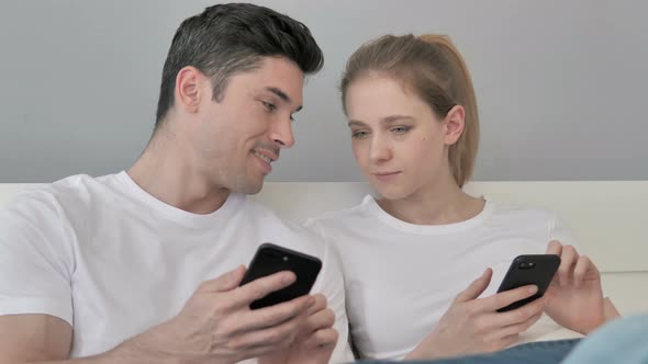 Couple Using Smartphone Together in Bed