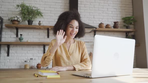 Happy African American Young Woman Looking at Computer Screen, Waving Hello. Pleasant Attractive