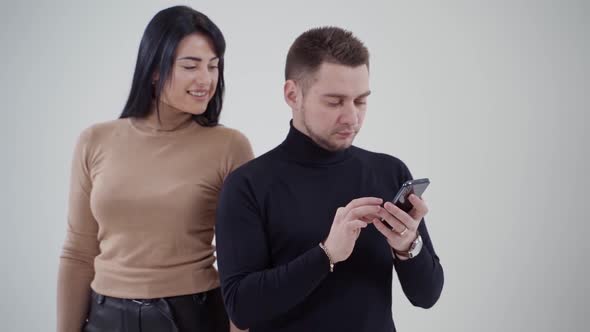 Young happy couple looking at a phone in studio.