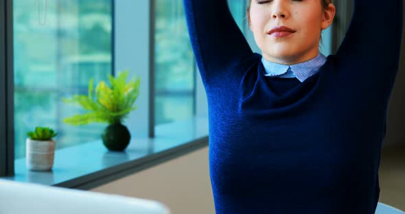 Female executive stretching her hands while working in office