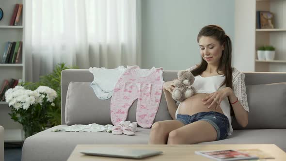 Pregnant Female Holding Teddy Bear Close to Belly, Rubbing It Gently, Baby Toys