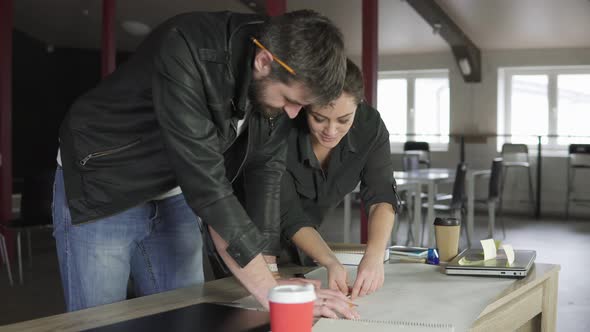 Young Man and Woman Working on a Project Drawing and Thinking in Modern Office