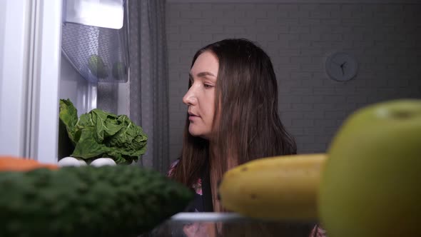 Woman Vegan Looks for Snacks and Takes Carrot From Fridge