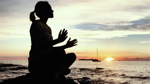 Silhouette Young Woman practicing Yoga on the Sunset Beach.