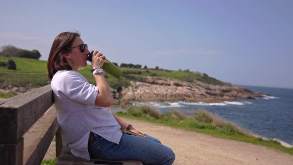 The Girl Sits on Benches Near the Ocean and Drinks Tea