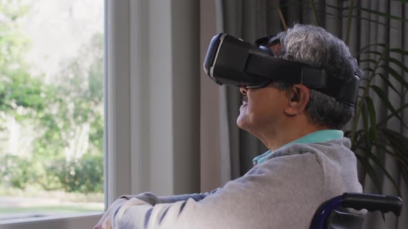 Happy mixed race senior man wearing vr headset and having fun at home