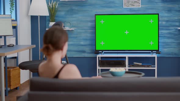 Woman Sitting on Sofa Looking at Green Screen on Tv Relaxing Watching Movie in Modern Living Room