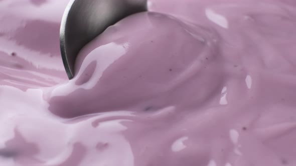 Berry yogurt with spoon, blueberry yogurt close up