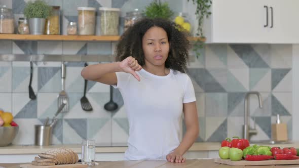 African Woman Showing Thumbs Down While Standing in Kitchen