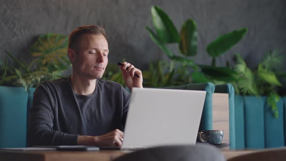 Thoughtful Serious Young Man Student Writer Sit at Home Office Desk with Laptop Thinking of