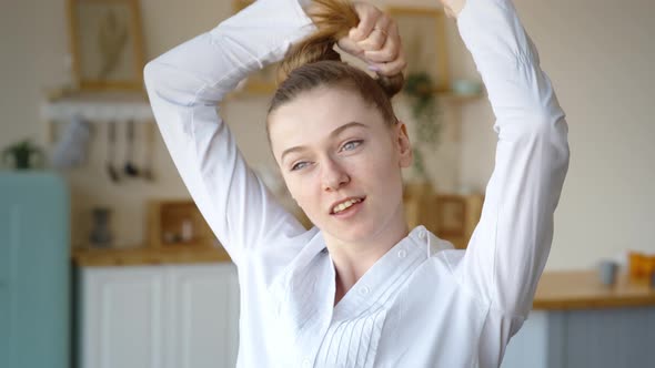 Attractive Cheerful Woman Dancing on Bed and Singing with Comb Like Microphone at Home