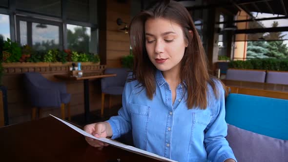 Pretty Woman Reading Menu at Restaurant with  Face in .