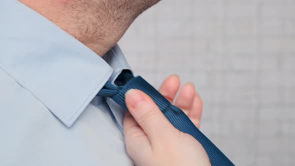 Caring wife straightens blue tie on collar of shirt businessman