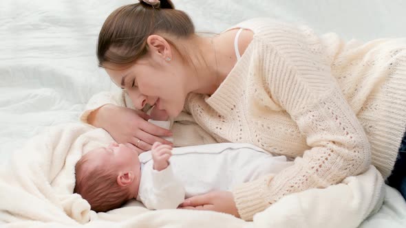 Top View of Beautiful Smiling Mother Lying Next To Her Newborn Baby and Looking on Son