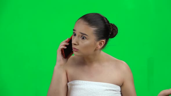 Young Woman with Bare Shoulders in White Towel Speaks By Cellphone and Is Angry, Green Screen. Slow