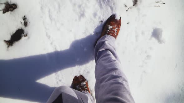 Close-up. Man walking on snow brown winter boots and gray sweatpants. The snow,