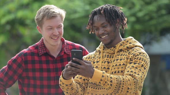 Young Multi-ethnic Friends Using Phone Together in the Streets Outdoors