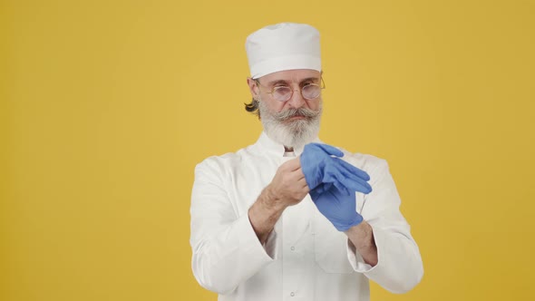 Man in Medical Hat Put on Disposable Gloves on Copy Space