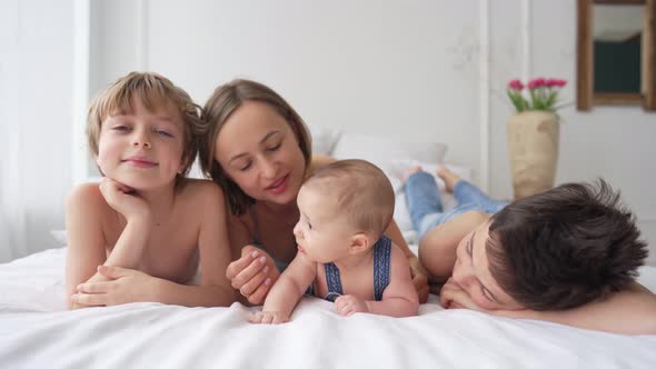 Mom and Three Sons are Having Fun on a White Bed