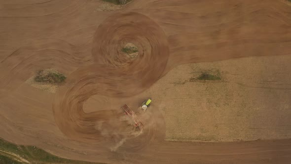 Shooting From a Drone. The Tractor Is Plowing the Ground, Drawing a Circle. Preparing for Sowing