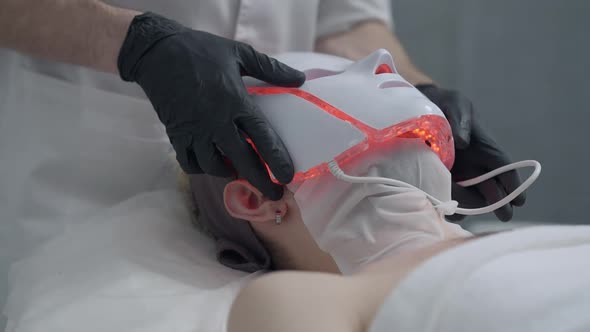 Closeup Applying of LED Light Therapy Device on Face of Young Man in Beauty Parlor