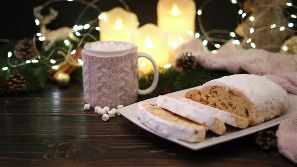 Sliced Traditional Christmas Stollen Cake with Marzipan and New Year Decorations on Wooden