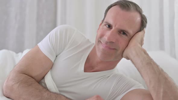 Close Up of Cheerful Middle Aged Man Smiling at the Camera in Bed