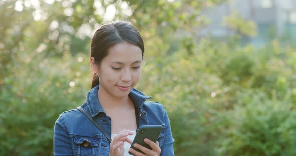 Woman work on mobile phone in city at park