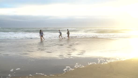 Group of friends at beach playing in surf