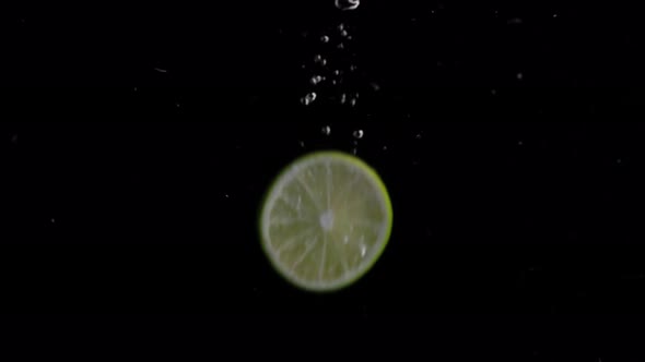 Lime Slice Falling into Water Super Slowmotion, Black Background, lots of Air Bubbles, 4k240fps