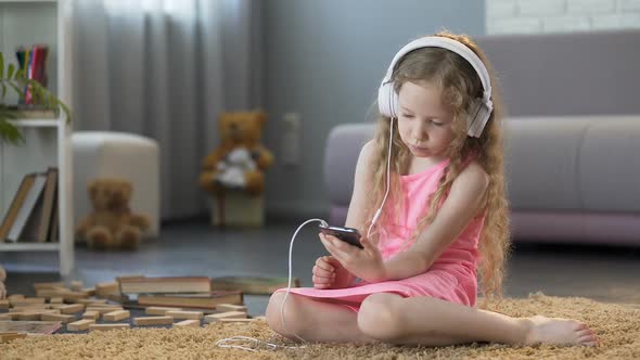 Kid in Headphones Listening to Music on Smartphone, Addicted to Technology