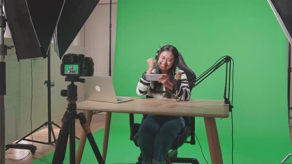 Camera Recording Happy Asian Woman Celebrating Winning The Mobile Phone Game On The Green Screen