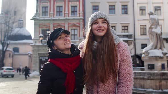 Two Smiling Women Tourists Walking Together on City Street Family Couple Talking Embracing