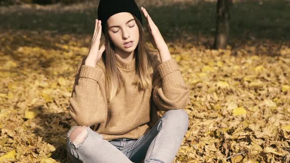 Carefree Teen Relaxing and Posing on Autumn Lawn in a Park