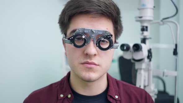 Satisfied Young Man Smiling Looking at Camera As Doctor Putting on Trial Frame