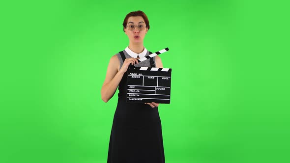 Funny Girl in Round Glasses Is Holding a Movie in Her Hands. Green Screen