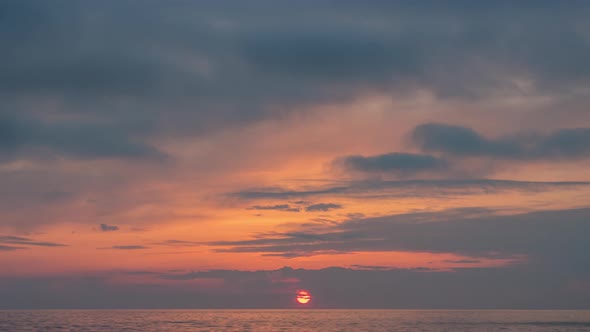 View of Sunset sun and clouds above sea.