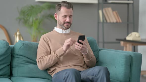 Man Having Success on Smartphone at Home