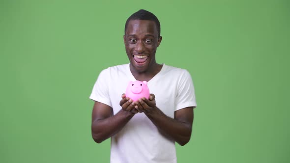 Young African Man Holding Piggy Bank