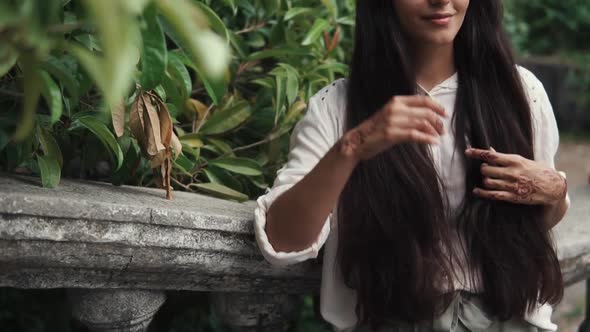 Charming Dark-haired Woman Is Resting in a Park , Close-up of Hands and Hairs