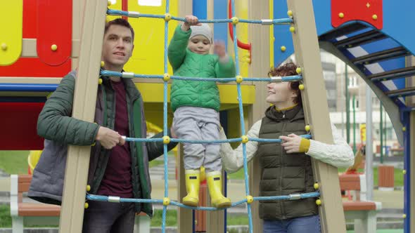 Happy Caucasian Couple and Son Posing Together at Playground alt