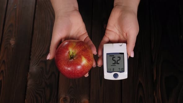 Closeup of a Woman Holding an Apple and a Glucometer with a Good Blood Sugar