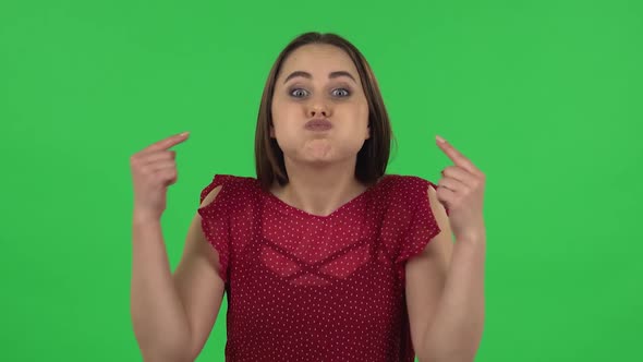 Portrait of Tender Girl in Red Dress Is Posing for Camera Making Funny Faces. Green Screen
