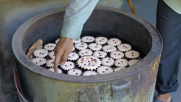 Baker touching Khanom Farang Kudeejeen cupcakes in tandoor-like oven with his finger