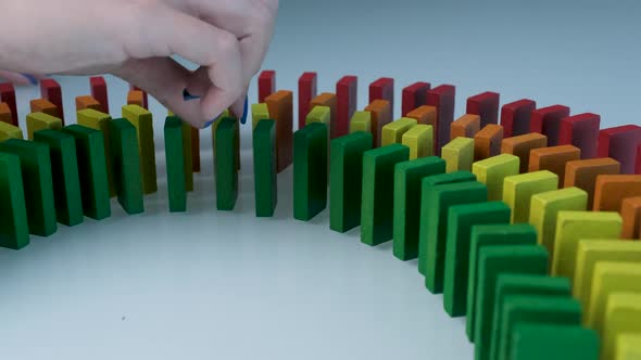 Line up of Dominoes in Rainbow Falling Colors with LGBT Colors of a Hand